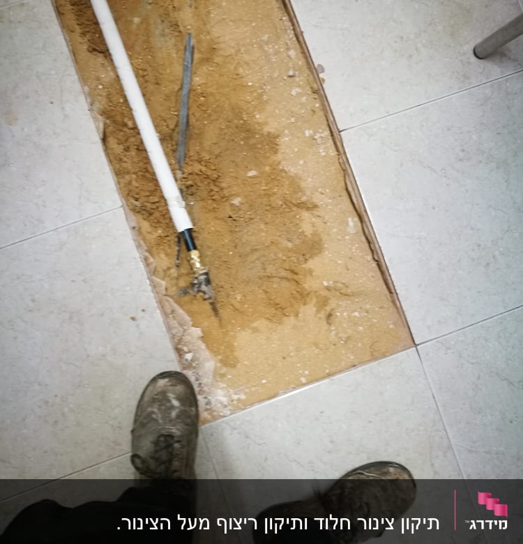צינור לבן מונח בתעלה על רצפה